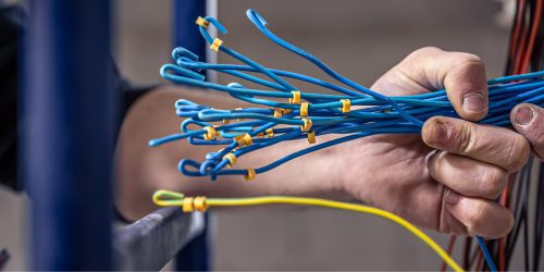 male-electrician-works-switchboard-with-electrical-connecting-cable